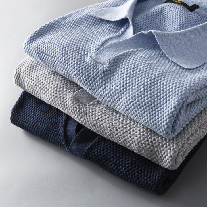 Display of multiple men's premium polo shirts in sky blue, navy, gray, olive green. Tailored & breathable.