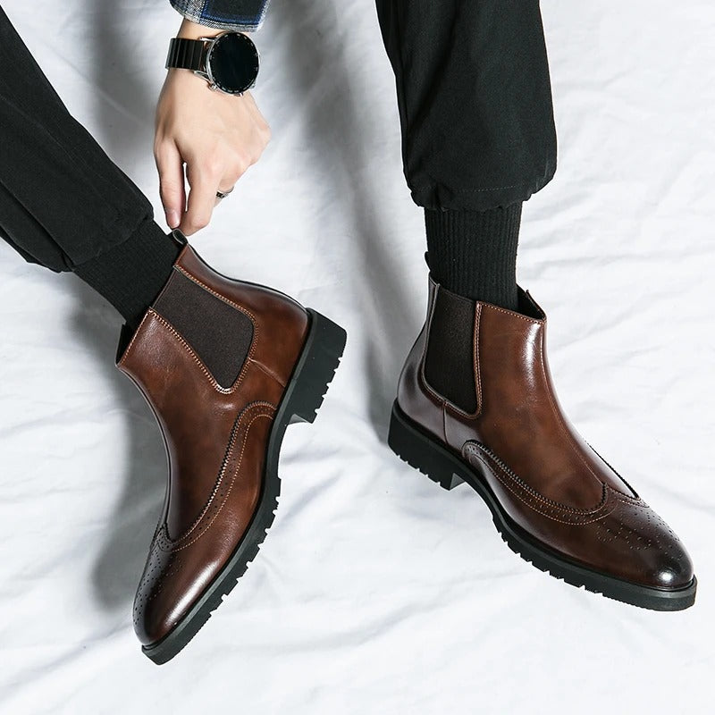 Side view of men's sleek chelsea boots, highlighting the elastic gussets and brogue perforations.