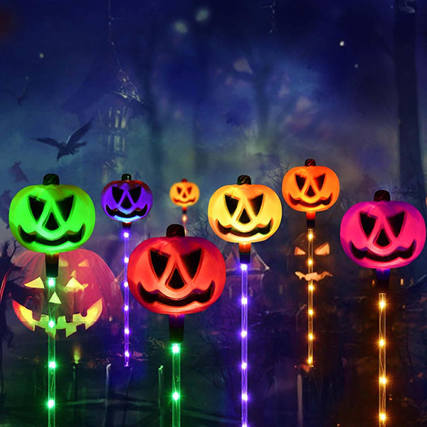 Overhead shot of 6 solar LED Halloween ground lights, casting spooky patterns on a garden lawn
