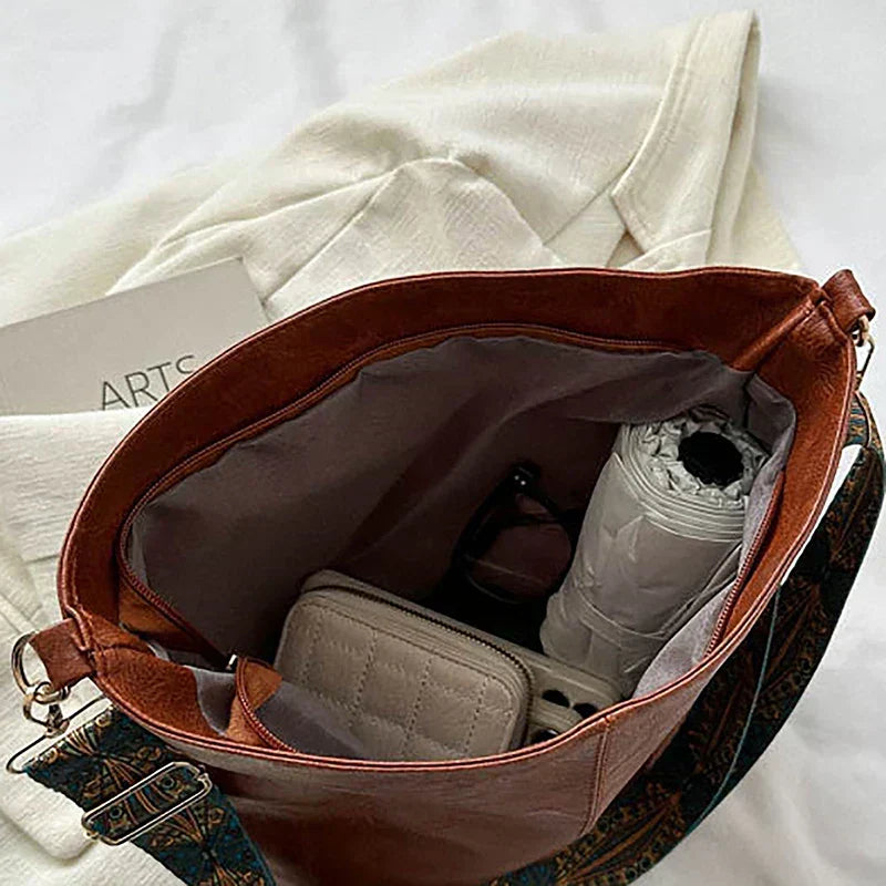Slouchy women's bohemian shoulder bag made from synthetic leather with a cool patterned strap.