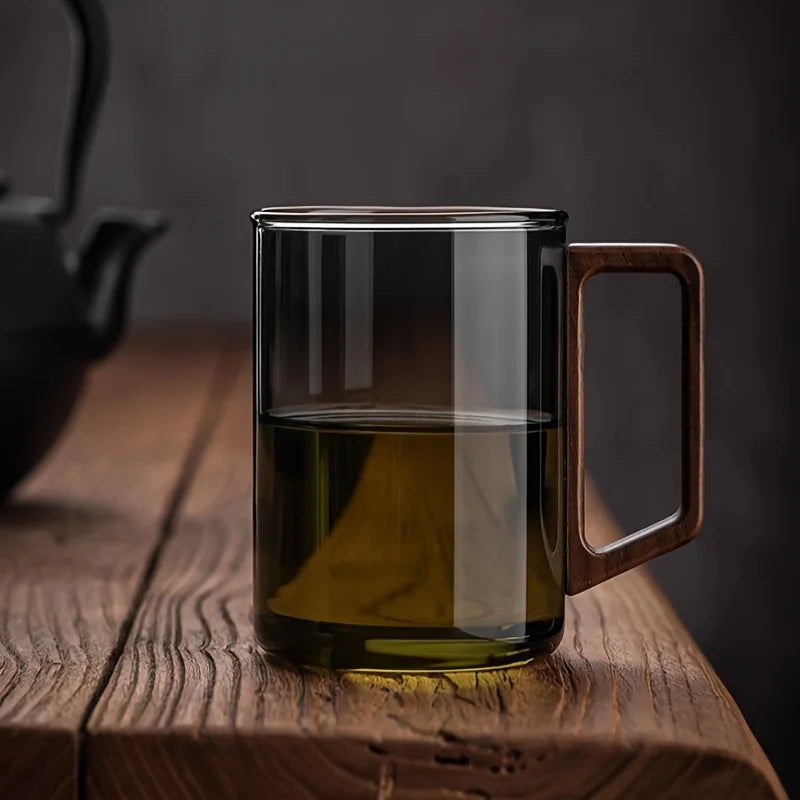 Smoke gray glass coffee mug featuring a stylish walnut handle. Perfect borosilicate drinkware for tea.