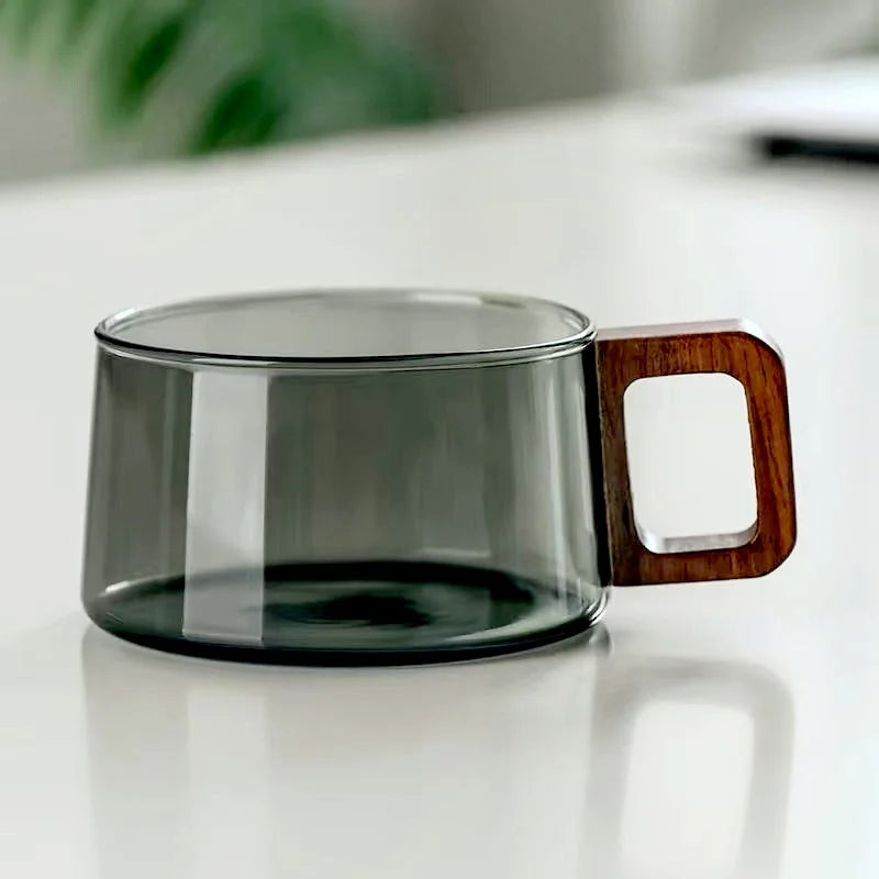 Stylish transparent glass tea cup with a natural wood handle, ideal for modern kitchen decor.