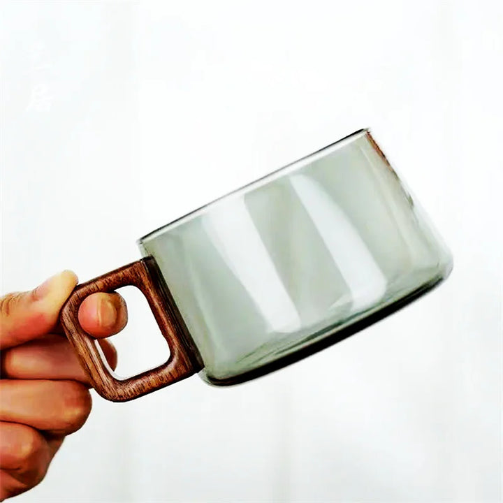 Close-up of a minimalist glass drinkware item with a distinctive light wood handle.