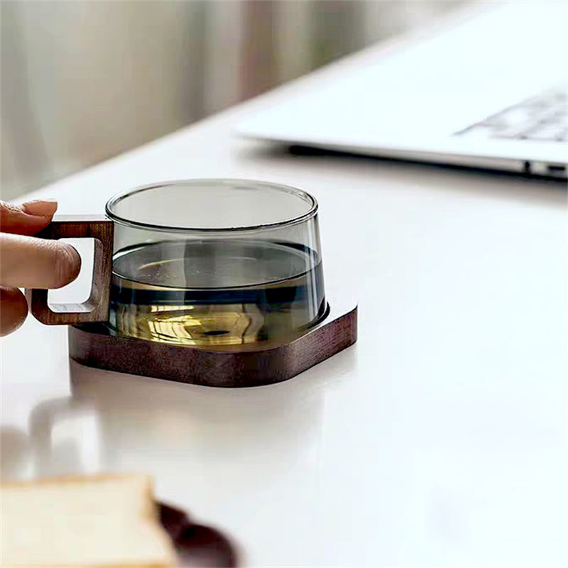Elegant glass coffee mug featuring a unique ergonomic wooden handle for comfortable grip.