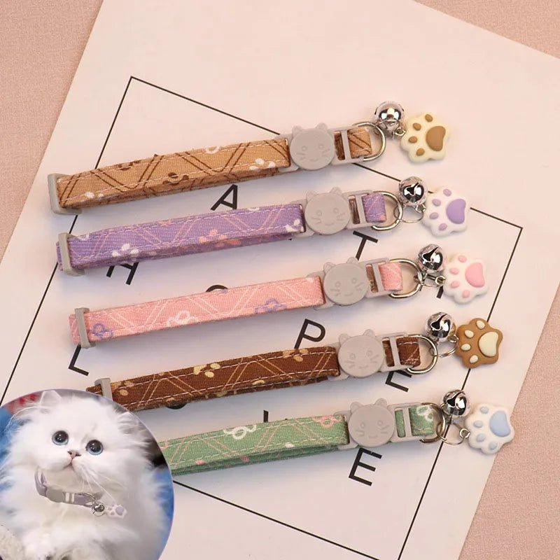 Green polyester adjustable cat collar featuring a paw print design and a silver safety bell.