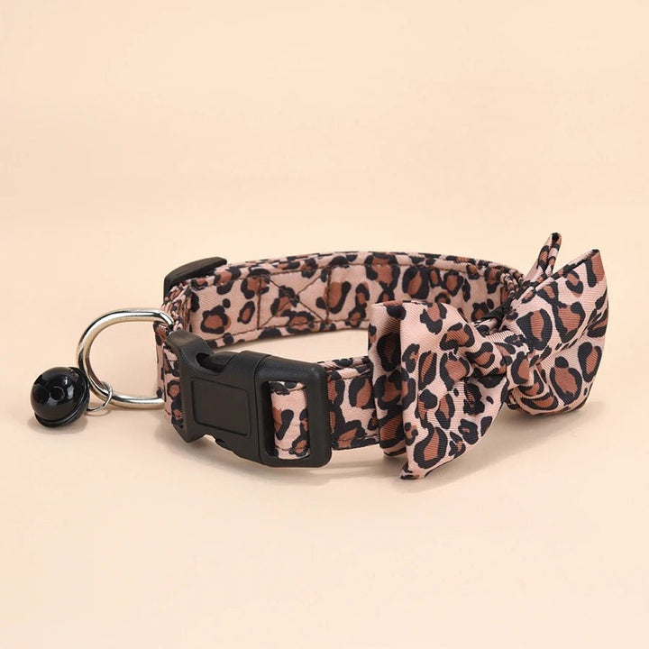 Adjustable leopard print pet collar with removable bow and bell for small dog or cat, made of lightweight twill fabric.