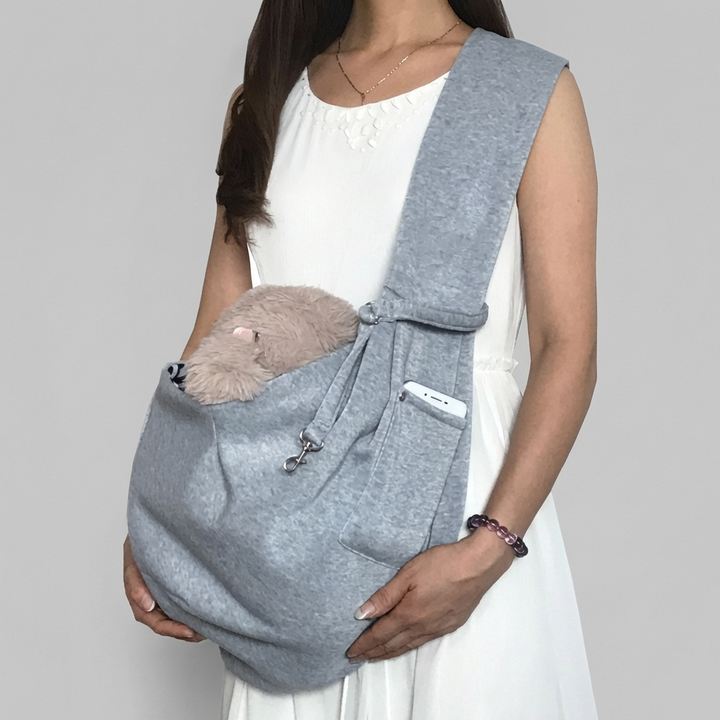 Owner carrying a happy small dog in a comfortable, adjustable pet sling carrier for easy travel.