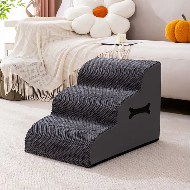 Two small dogs using the gentle ramp of adjustable soft pet stairs to reach sofa
