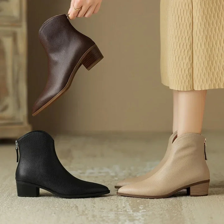 Woman wearing pointed toe slip-on ankle boots in a city setting. Chic fall/winter everyday footwear.