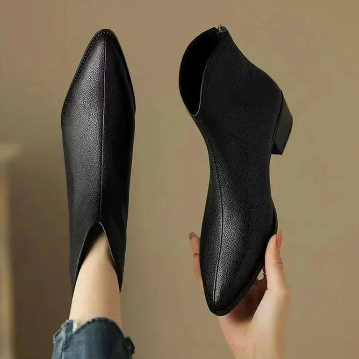 Woman standing in stylish black pointed toe slip-on ankle boots. Perfect for office wear & fall fashion.