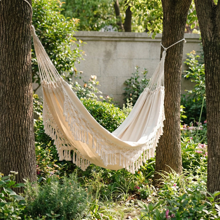 Bohemian tasseled outdoor hanging hammock chair for single person relaxation in garden or patio.