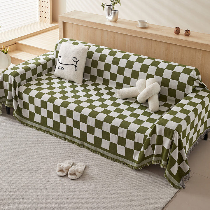 Close-up of a black and white checkerboard couch cover with decorative fringe, perfect for home decor.