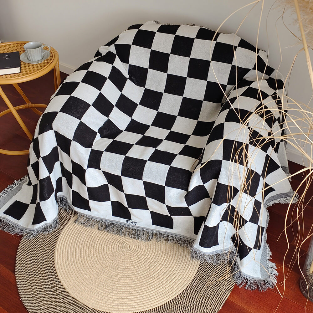 Soft polyester checkerboard sofa blanket with distinct fringe, enhancing living room aesthetics.