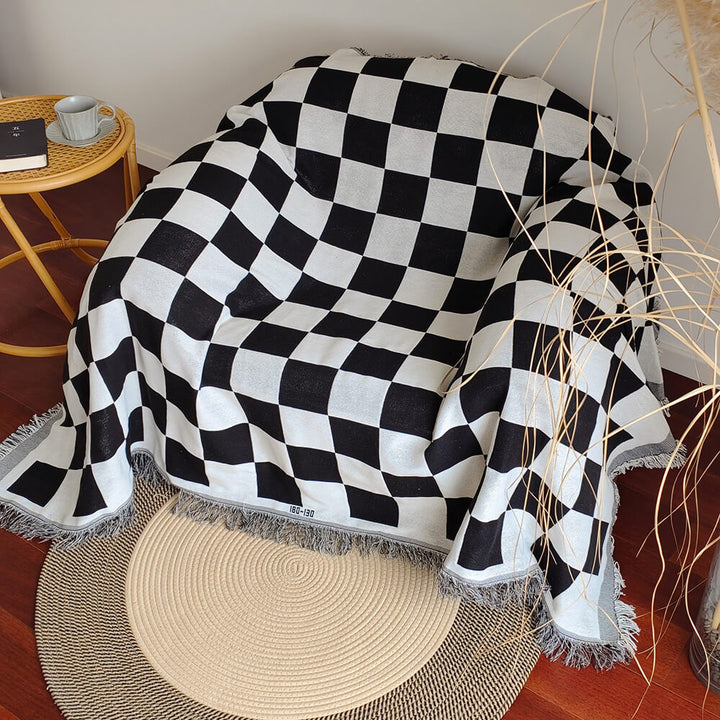 Soft polyester checkerboard sofa blanket with distinct fringe, enhancing living room aesthetics.