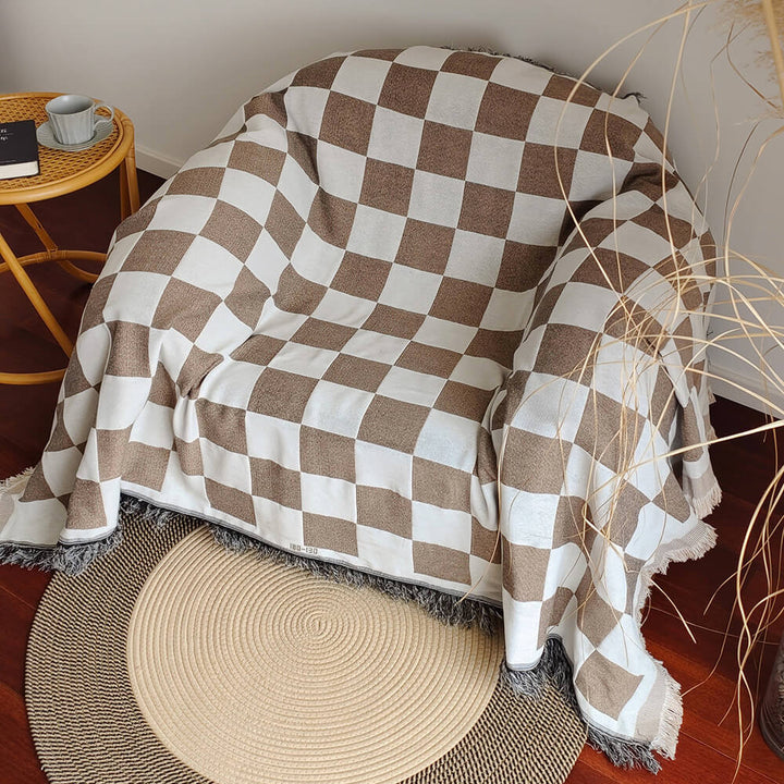 Home decor accent: a checkerboard sofa cover with elegant fringe detailing, ideal for living room refresh.