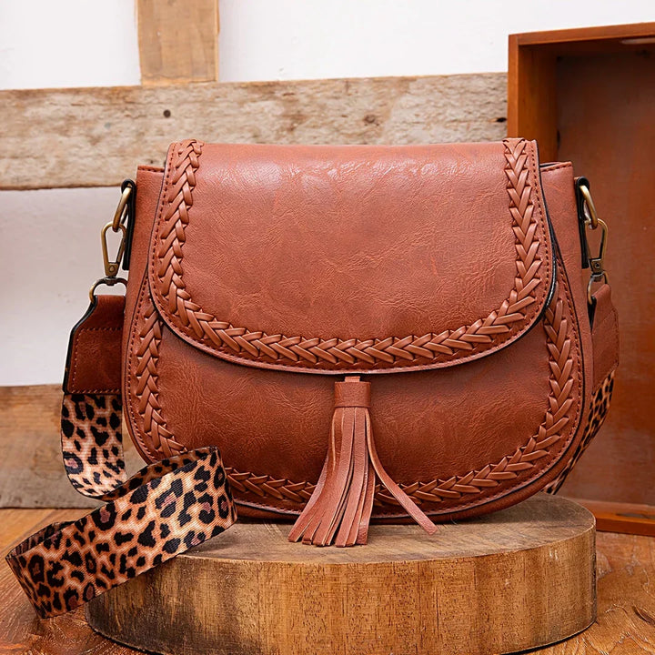 Chic brown women's saddle bag with tassel detail & adjustable strap.