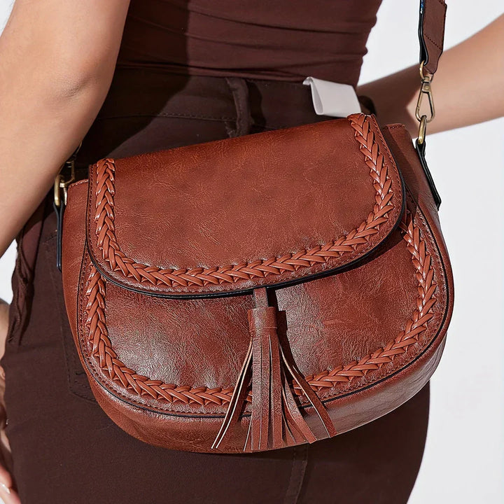 Stylish women's brown saddle bag, featuring prominent tassel and comfortable adjustable strap.