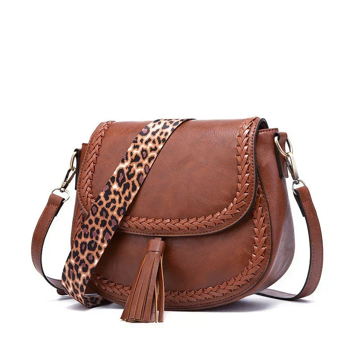 Chic black women's shoulder bag; a modern saddle bag with tassel accent & adjustable strap.