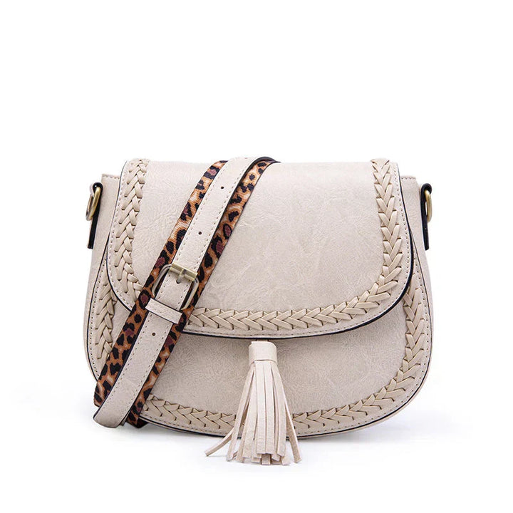 Women's brown crossbody saddle bag, featuring a chic tassel and adjustable strap for versatility.