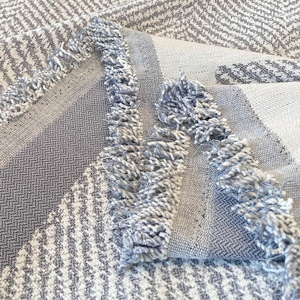 View of a living room with a cozy fringed chenille couch cover on the sofa, machine washable