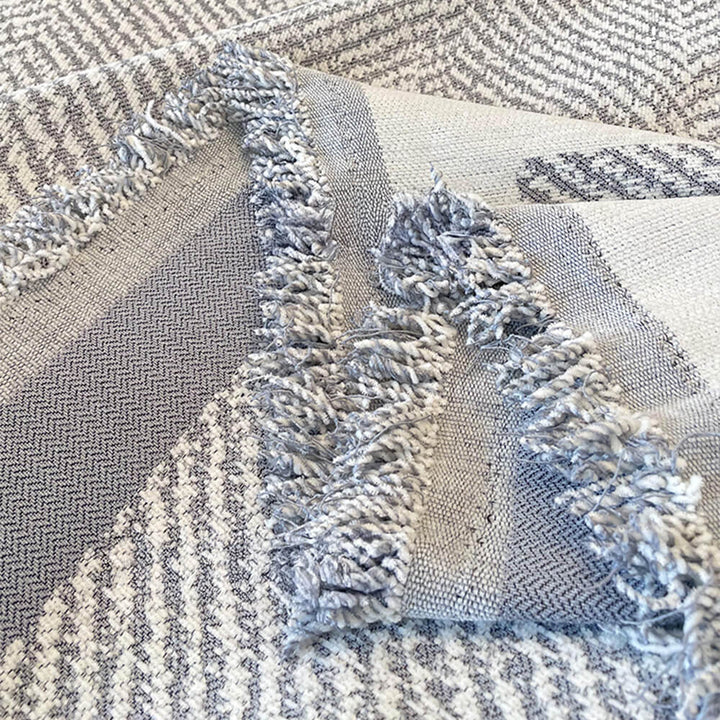 View of a living room with a cozy fringed chenille couch cover on the sofa, machine washable