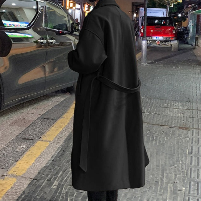 Close-up of the adjustable belt & buckle on a men's tailored long overcoat, emphasizing classic style.