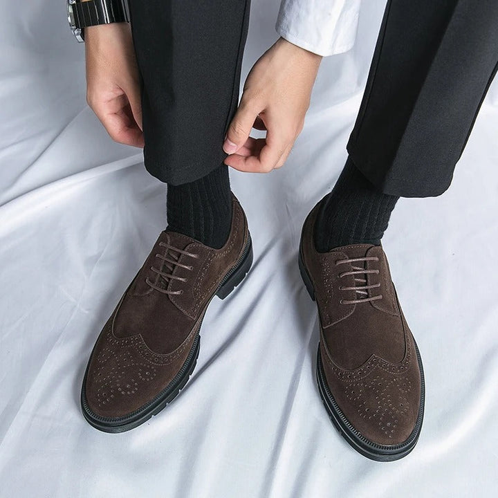 Detail shot: textured suede and brogue perforations on a classic men's dress shoe.