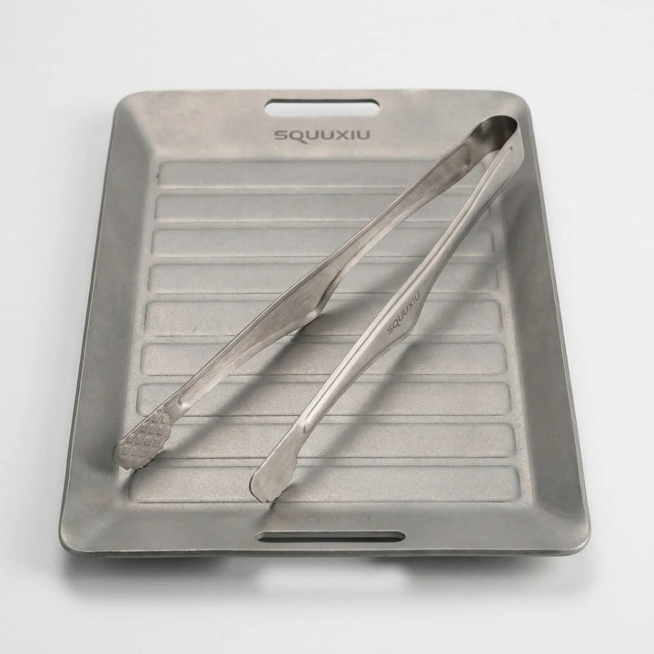 Lightweight compact grill plate with tongs for backpacking and outdoor culinary experiences.