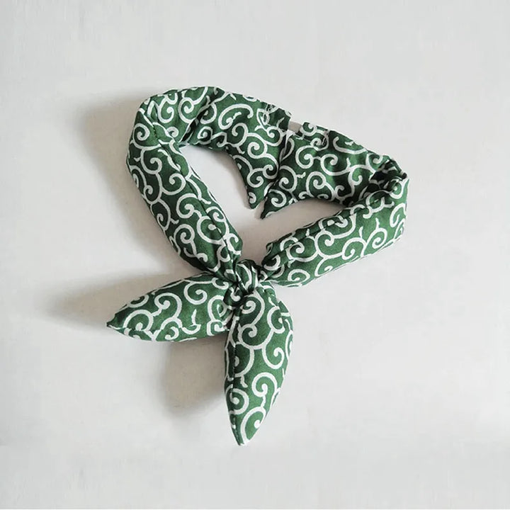 Dog enjoying a walk, wearing a cooling bandana with a classic traditional pattern for summer.
