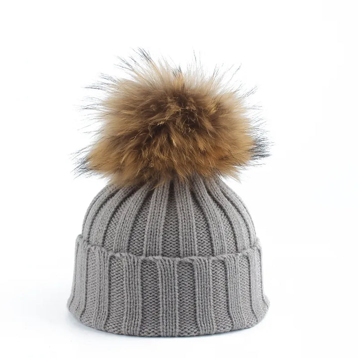 Stylish women's knitted winter hat with a chic faux fur pom-pom, a cozy cold weather fashion accessory.