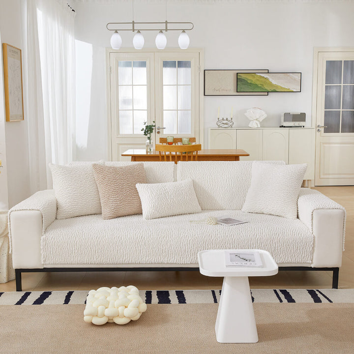 Pet friendly cream couch cover resisting scratches from a playful cat, furniture protection