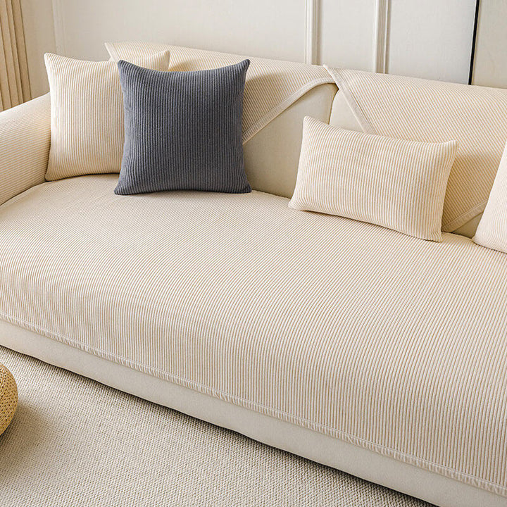 Full view of a living room with a cream vertical stripe fleece couch cover, enhancing home decor.
