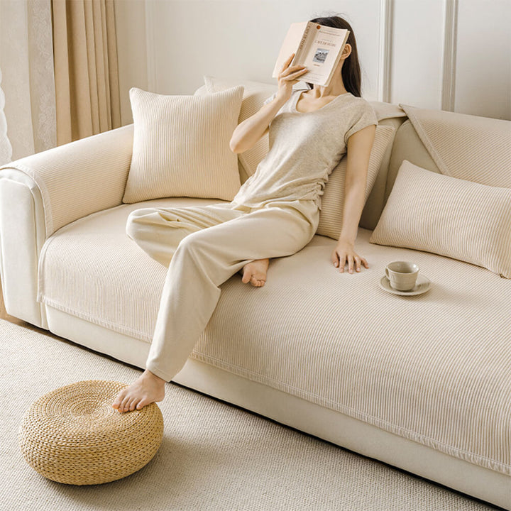 Packaging shot of a cream vertical stripe fleece sofa cover, emphasizing its pet-friendly features.