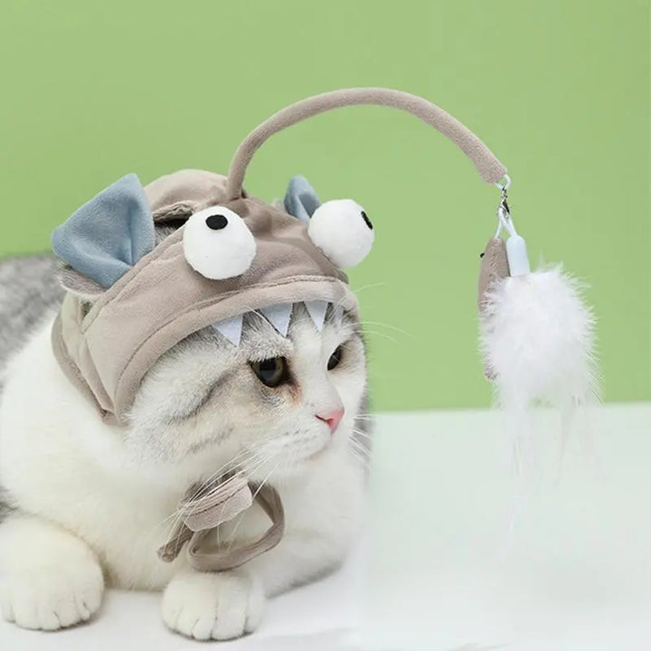 Orange tabby cat in a funny pet accessory, a cat hat with an attached feather for playtime.