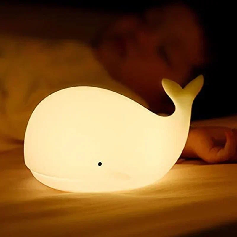 Whale night light showing its gentle color-changing glow, a soft silicone lamp for kids' bedtime.