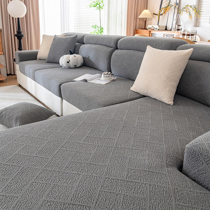 Full-cover stretch couch protector in a neutral color, fitting snugly on a three-seater sofa