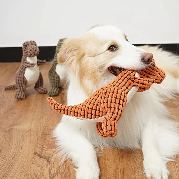 Dog happily playing with a green dinosaur plush chew toy. Interactive, durable dog toy for pets.