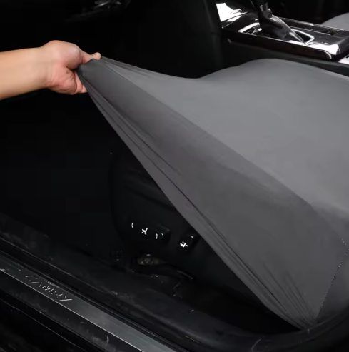 Texture shot of the scratch-proof surface of a black pet car seat cover, ideal for active dogs during travel.