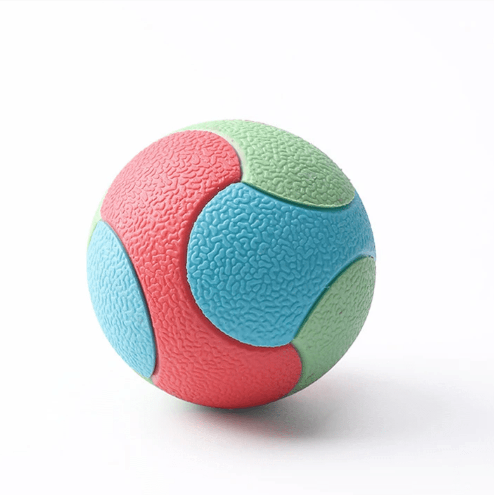Dog happily playing with a red durable interactive chew ball toy, showcasing its teeth cleaning features.