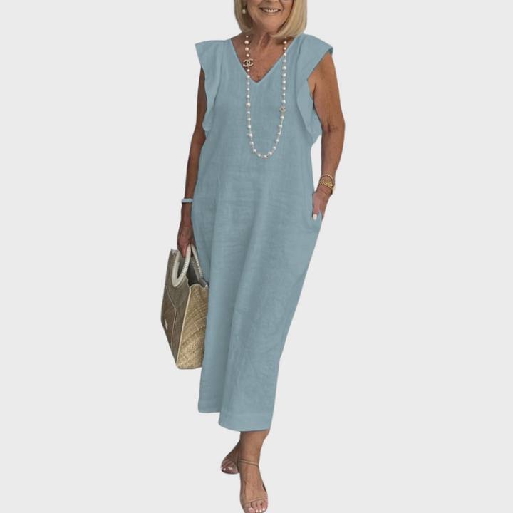 White women's flowy V-neck maxi dress with sleeveless cut, ruffle shoulders, and pockets, perfect for beach trips.