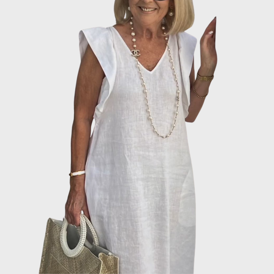 Flowy women's white maxi dress, featuring ruffle shoulders, V-neck, and pockets, ideal for beach or resort.