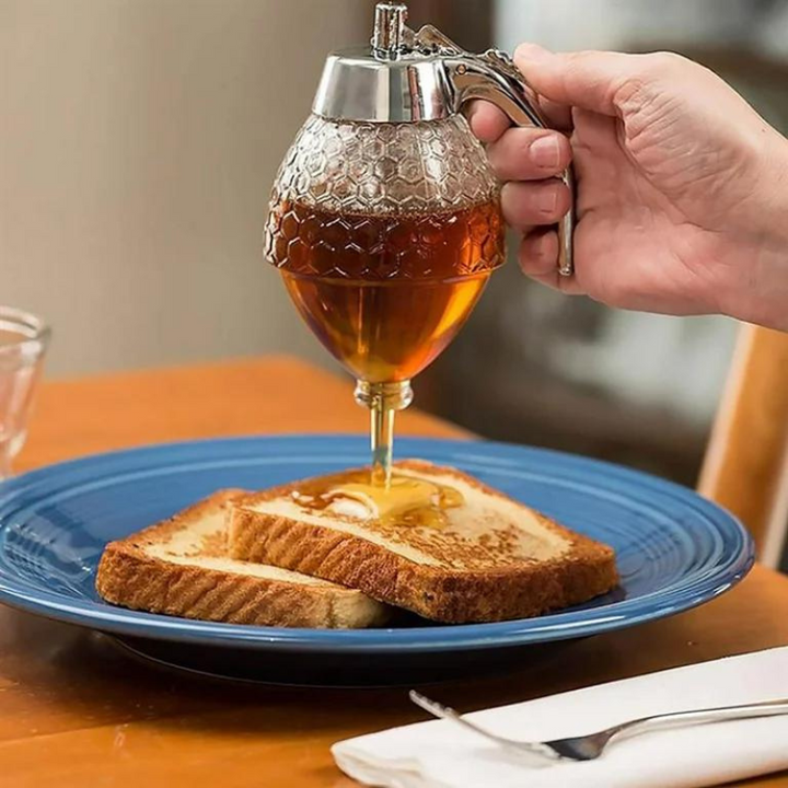 Transparent plastic drip-free honey dispenser with an elegant design, ideal for kitchen countertop display.