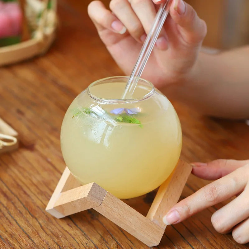 Unique Moon Ball glassware tumblers, ideal for sophisticated drinks & stylish kitchen decor, featuring a round glass & wood stand.
