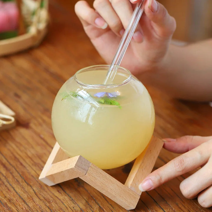 Unique Moon Ball glassware tumblers, ideal for sophisticated drinks & stylish kitchen decor, featuring a round glass & wood stand.