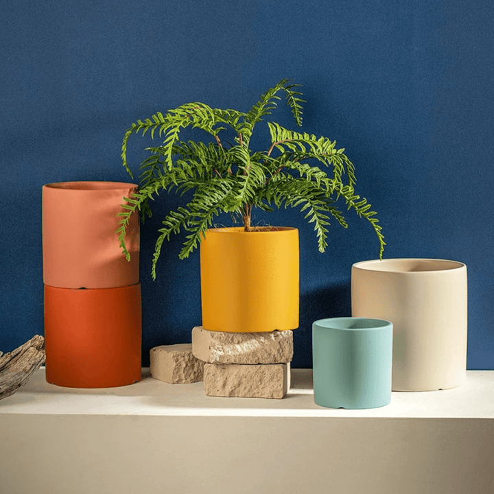 Round ceramic plant pot with matching saucer, ideal for modern home decor.