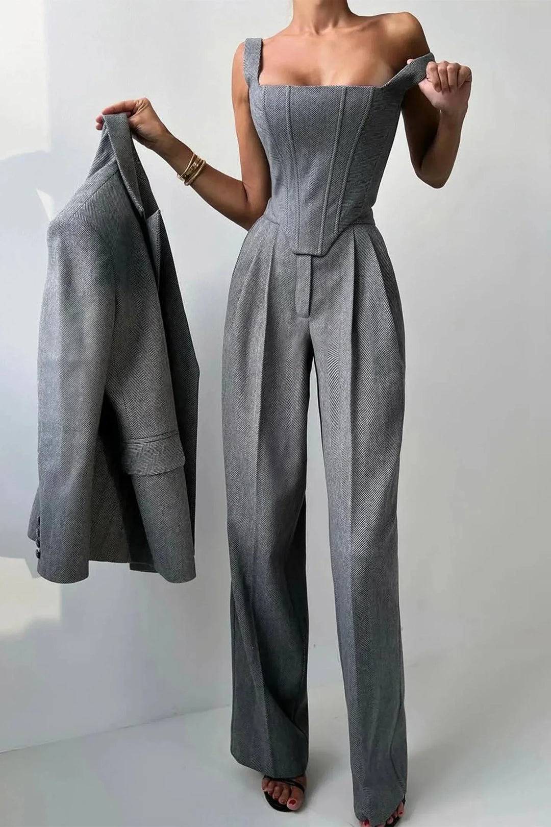 Sophisticated women's pink three-piece outfit including a structured corset, flowing wide-leg pants & a relaxed blazer.