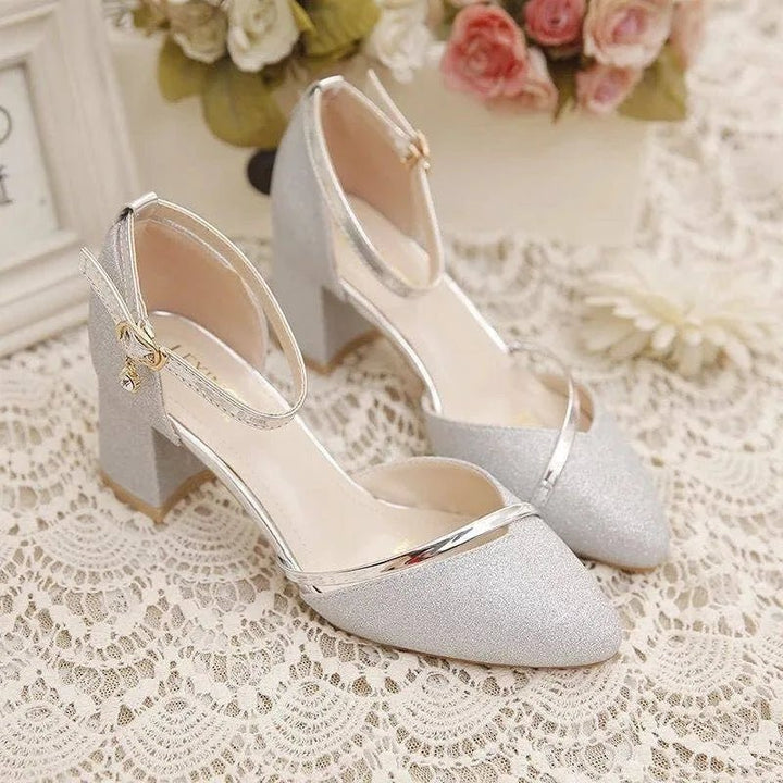 Silver women's block heel pumps with ankle strap, offering stable and chic versatile footwear.