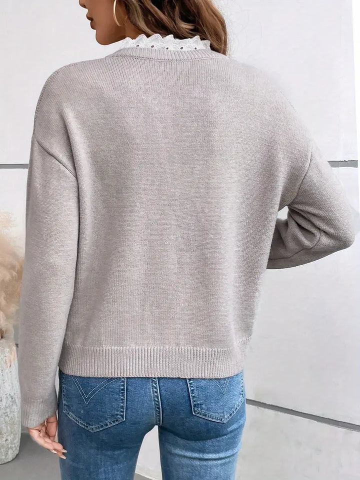 Front view of an elegant women's grey V-neck pullover sweater, showcasing its soft knit fabric and delicate lace trim.