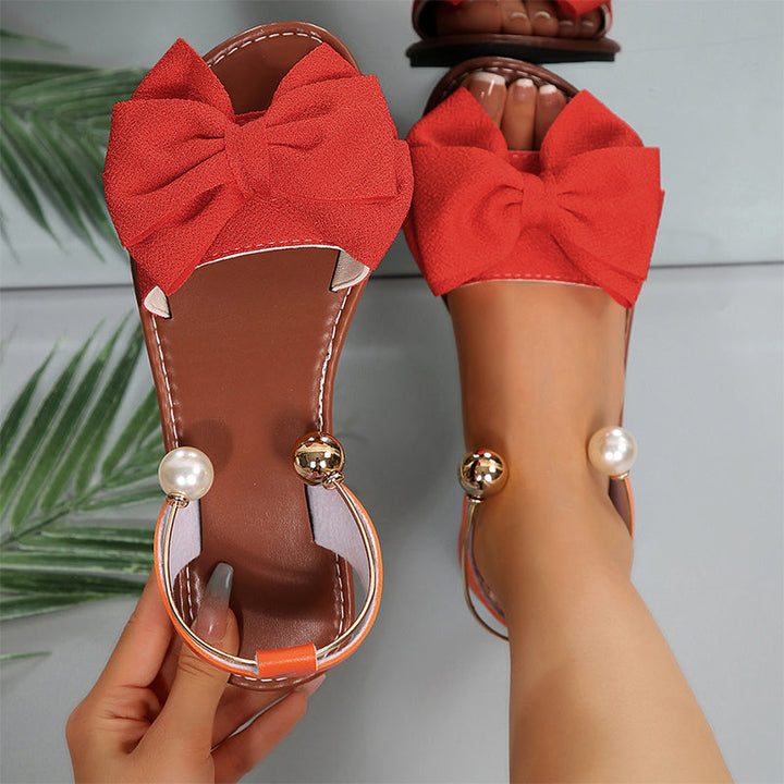 Stylish open-toe flat sandals for women, adorned with an elegant bow and shimmering bead accents.