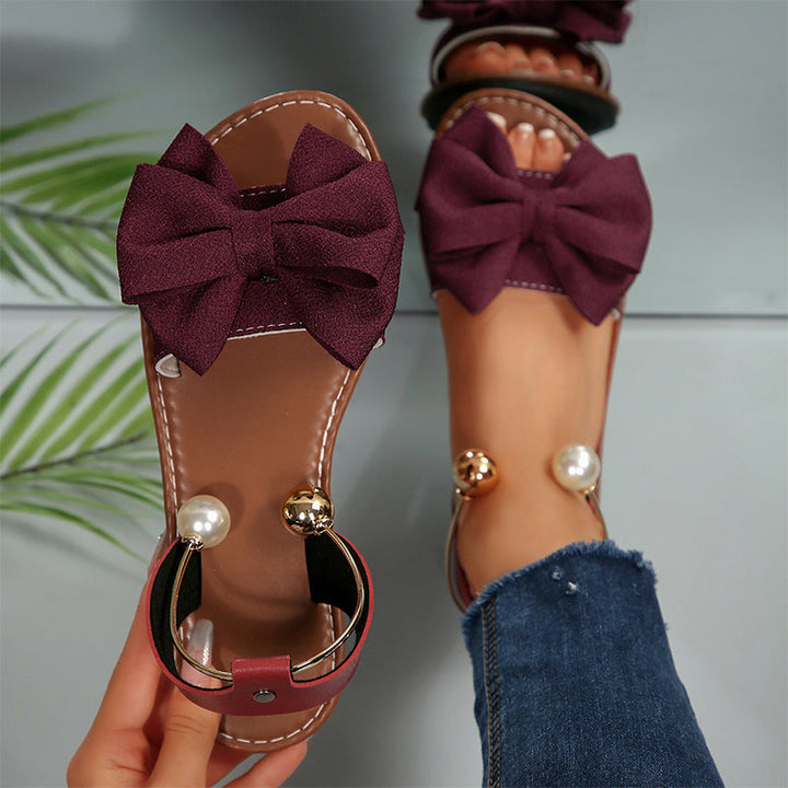 Slip-on women's flat sandals with elegant bow & bead accents, comfortable & stylish for summer casual wear.